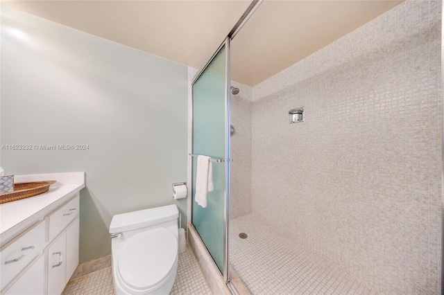 bathroom featuring a shower with door, vanity, tile patterned floors, and toilet