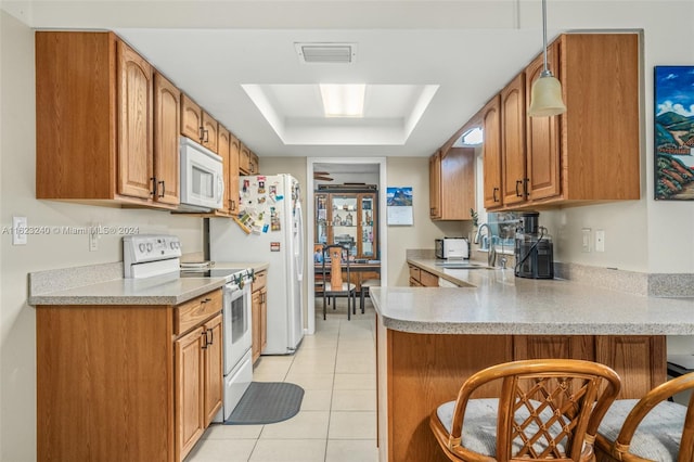 kitchen featuring light tile patterned floors, a tray ceiling, white appliances, sink, and kitchen peninsula