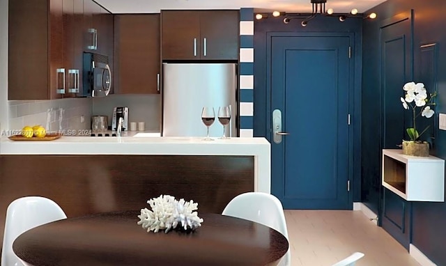 kitchen featuring backsplash, light tile patterned flooring, stainless steel appliances, and dark brown cabinetry