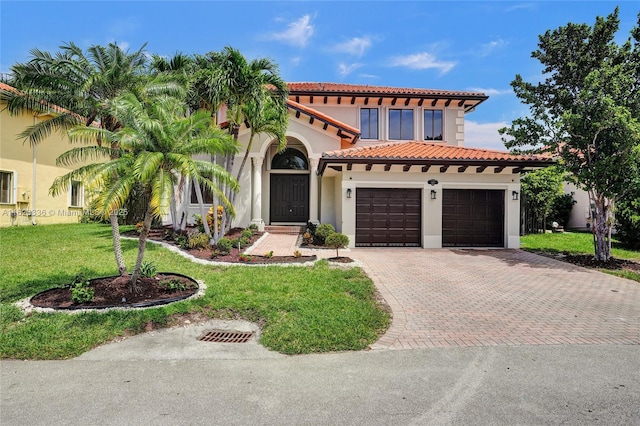 mediterranean / spanish home featuring a garage and a front lawn