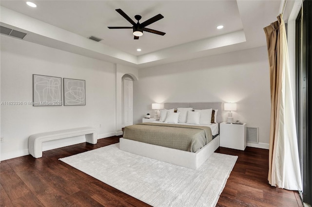 bedroom with a tray ceiling, dark hardwood / wood-style floors, and ceiling fan