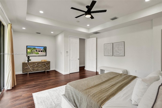 bedroom featuring a raised ceiling, dark hardwood / wood-style floors, and ceiling fan