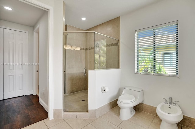 bathroom featuring a bidet, tile patterned floors, toilet, and a shower with door