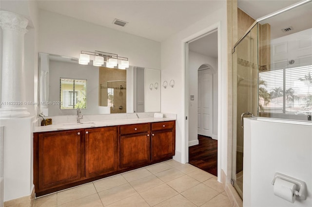 bathroom featuring tile patterned flooring, vanity, an enclosed shower, and decorative columns