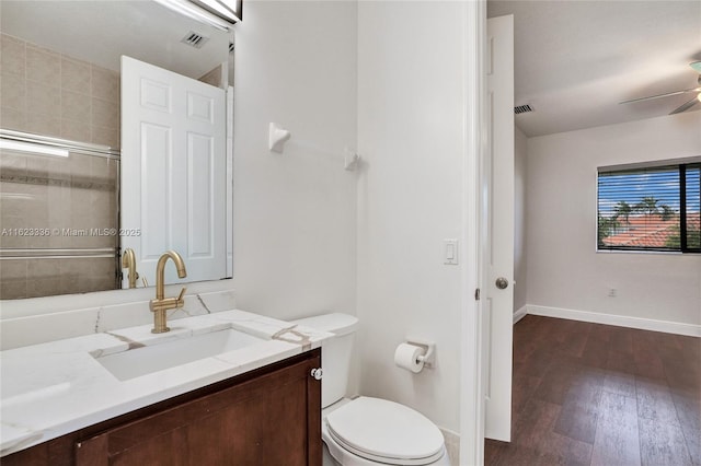 bathroom featuring hardwood / wood-style flooring, vanity, an enclosed shower, ceiling fan, and toilet