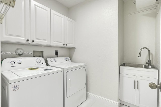 clothes washing area featuring cabinets, sink, and washer and dryer