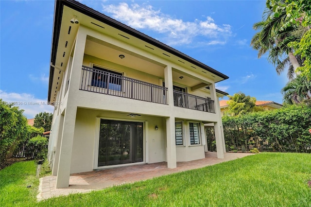 rear view of property with a balcony, a yard, and a patio