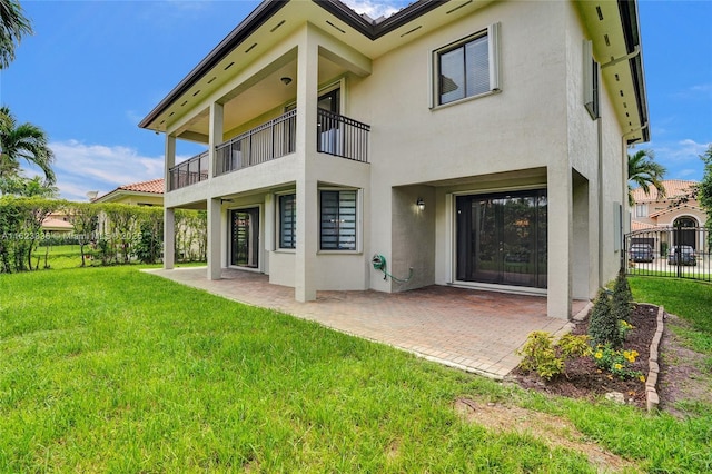 back of house featuring a lawn, a patio, and a balcony