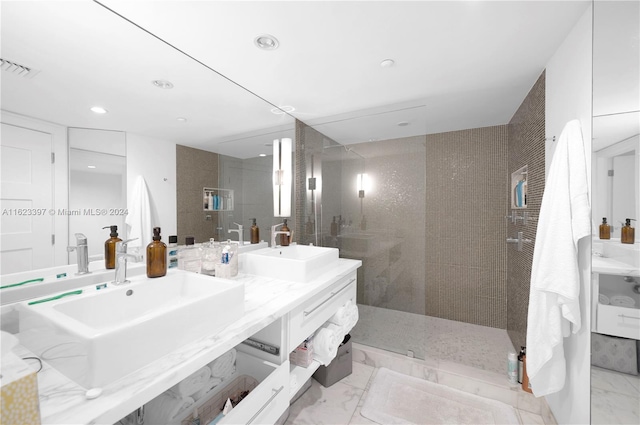 bathroom featuring double vanity, marble finish floor, a walk in shower, and a sink