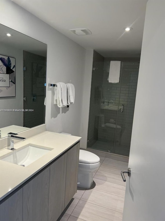 bathroom featuring tile patterned floors, vanity, a shower with door, and toilet