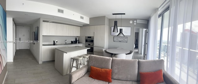 kitchen with pendant lighting, a breakfast bar area, a kitchen island, double oven, and tile patterned flooring