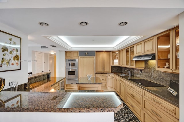 kitchen with black electric stovetop, dark stone countertops, a raised ceiling, double oven, and backsplash