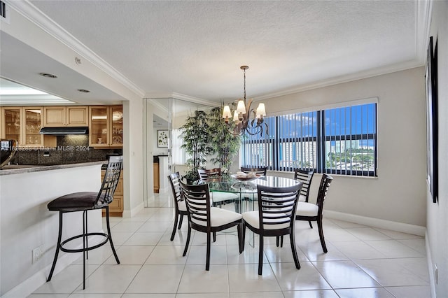 dining area with an inviting chandelier, a textured ceiling, ornamental molding, and light tile patterned floors