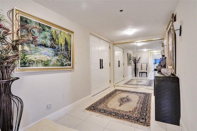 hall with light tile patterned flooring and a textured ceiling