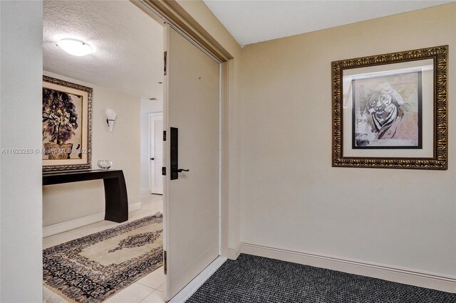 hallway featuring tile patterned floors and a textured ceiling