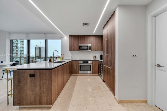 kitchen with sink, kitchen peninsula, stainless steel appliances, and a breakfast bar area