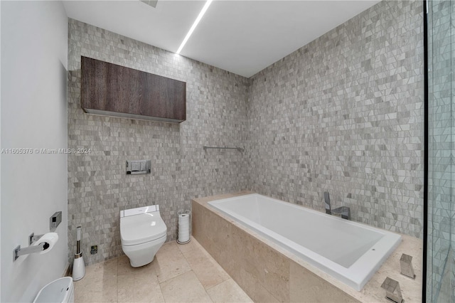 bathroom with tile patterned floors, tile walls, tiled bath, and toilet