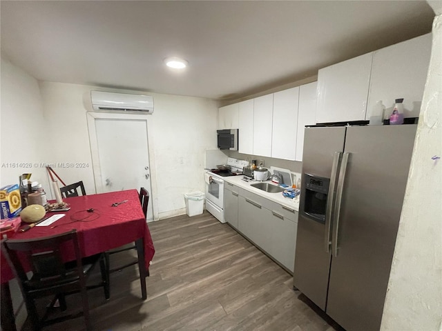 kitchen with appliances with stainless steel finishes, sink, dark wood-type flooring, white cabinetry, and an AC wall unit