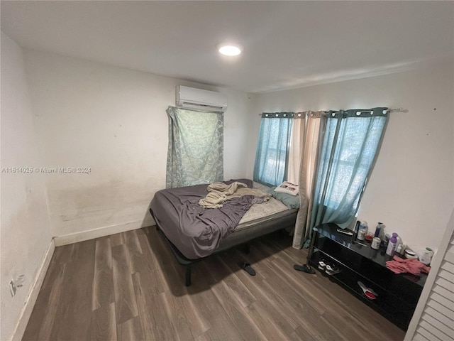 bedroom with a wall mounted air conditioner and hardwood / wood-style flooring