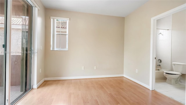 unfurnished bedroom with ensuite bathroom and light hardwood / wood-style floors