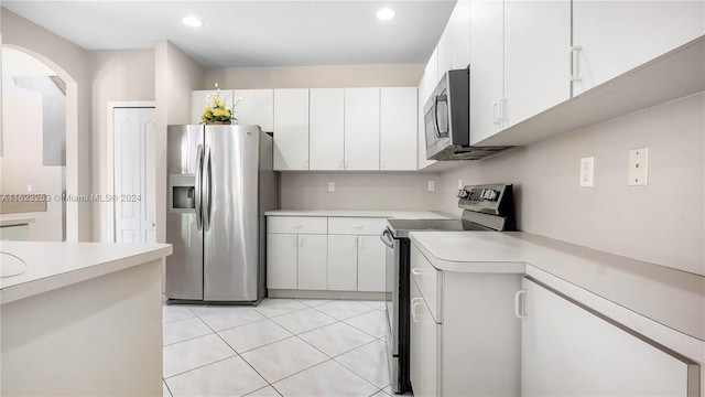 kitchen featuring light tile patterned floors, stainless steel appliances, and white cabinetry