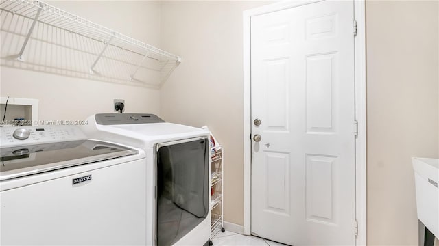 laundry room with light tile patterned flooring and washer and clothes dryer