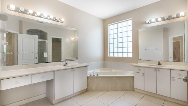 bathroom with tile patterned floors, independent shower and bath, vanity, and a healthy amount of sunlight