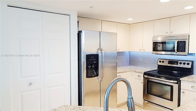 kitchen with light stone countertops, appliances with stainless steel finishes, and tasteful backsplash