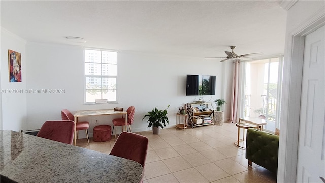 tiled living room featuring ceiling fan and crown molding