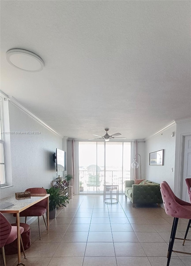 living room featuring ceiling fan, crown molding, light tile patterned floors, and a wall of windows