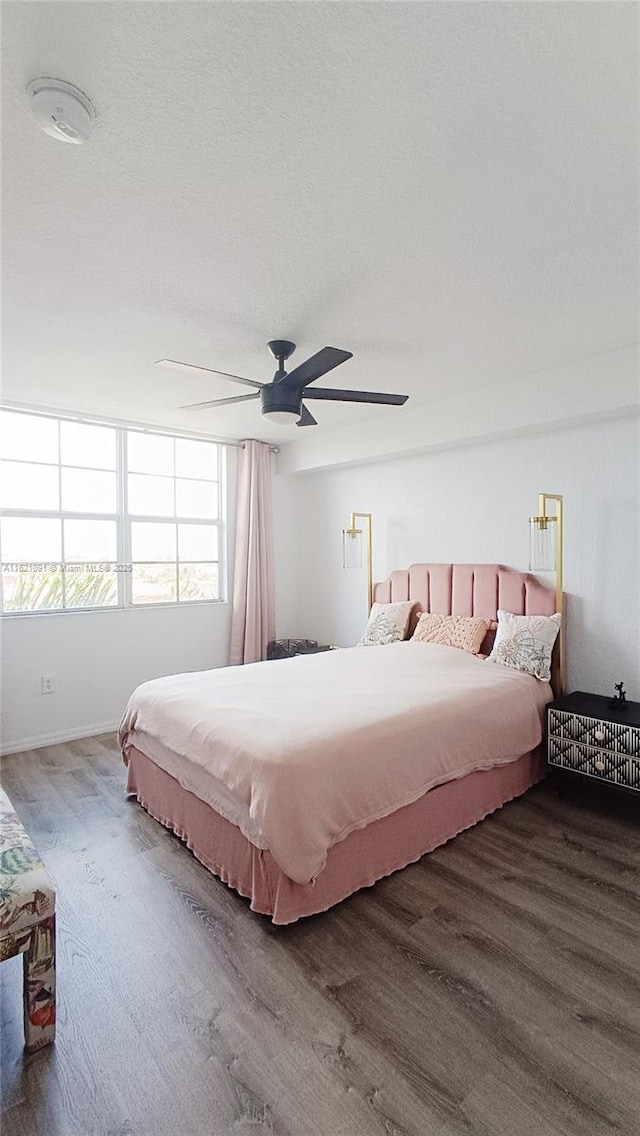 bedroom featuring baseboards, wood finished floors, and ceiling fan