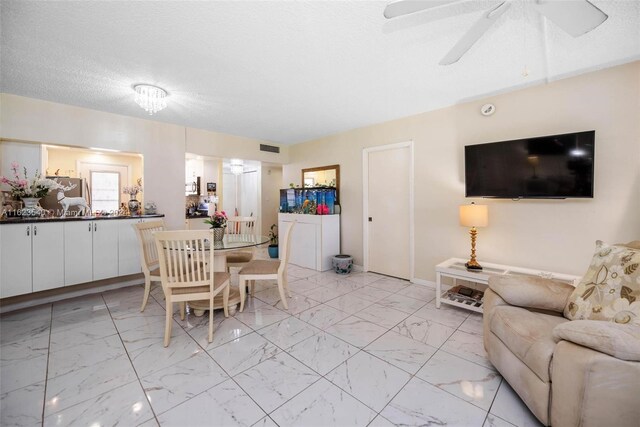 tiled dining space with a textured ceiling and ceiling fan