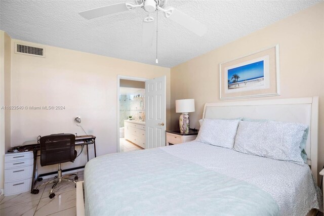 bedroom with light tile patterned floors, a textured ceiling, ceiling fan, and connected bathroom