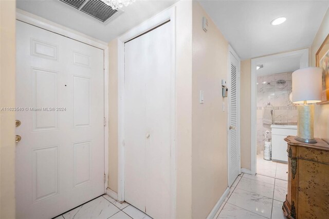 hallway featuring tile walls and light tile patterned floors