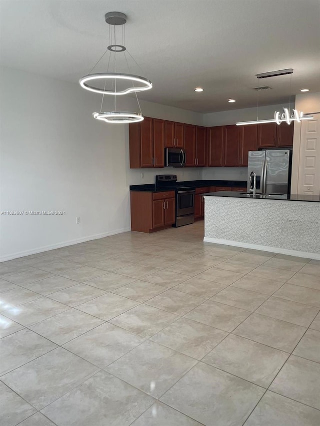 kitchen with a kitchen island, appliances with stainless steel finishes, pendant lighting, and light tile patterned floors