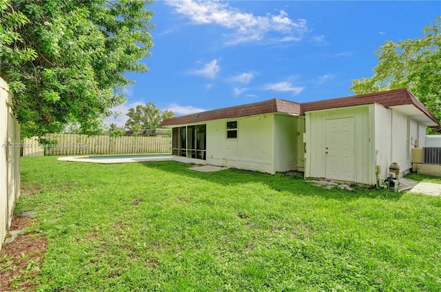 rear view of house featuring a yard and a fenced in pool