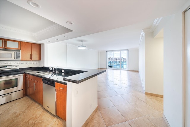 kitchen featuring crown molding, dark countertops, appliances with stainless steel finishes, a sink, and a peninsula