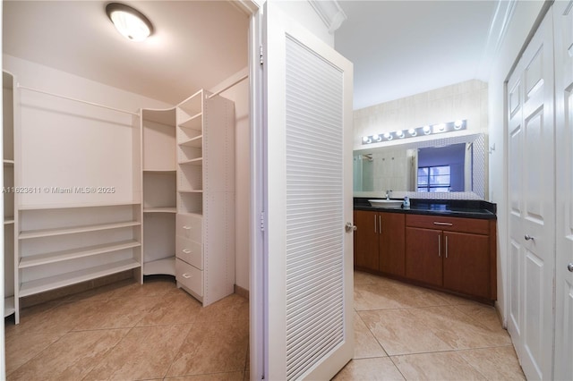 spacious closet featuring a sink and light tile patterned flooring