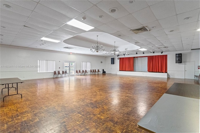 miscellaneous room featuring visible vents, baseboards, a drop ceiling, and a chandelier