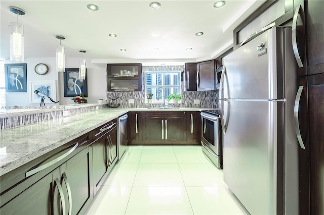 kitchen with light stone counters, dark brown cabinetry, stainless steel appliances, pendant lighting, and backsplash