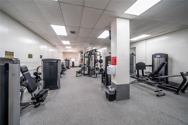 gym with a paneled ceiling and carpet