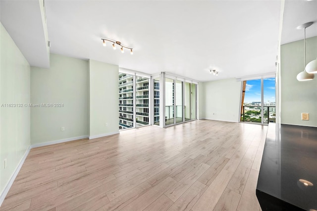 unfurnished living room featuring track lighting, light hardwood / wood-style flooring, and expansive windows