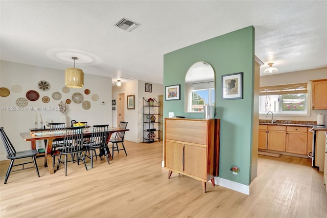 dining space with sink, a textured ceiling, and light hardwood / wood-style flooring