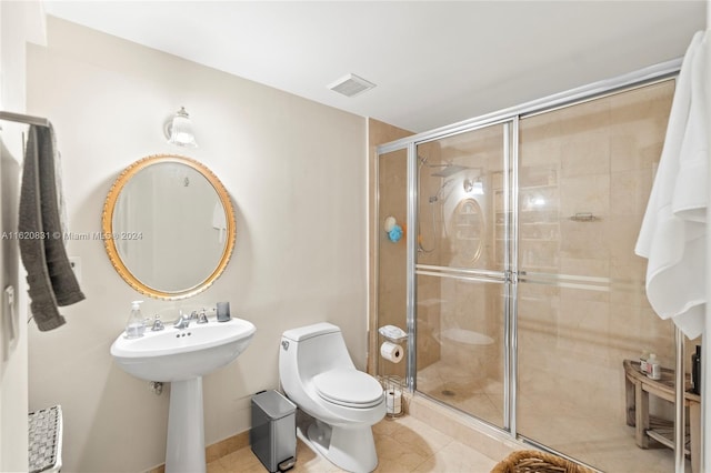 bathroom featuring tile patterned flooring, toilet, sink, and an enclosed shower