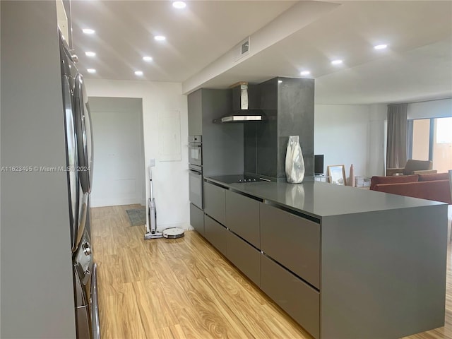 kitchen with wall chimney range hood, gray cabinets, and light hardwood / wood-style floors