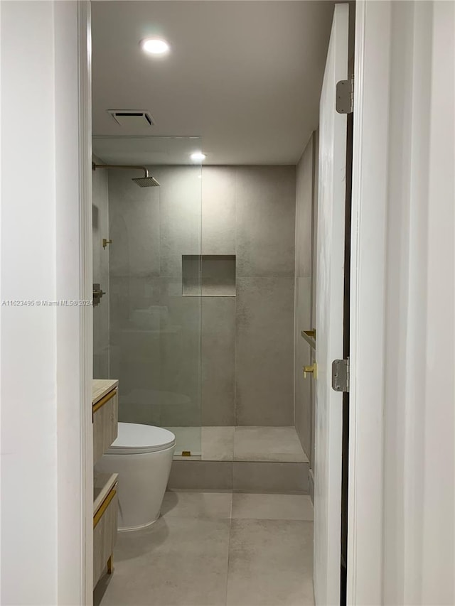 bathroom featuring toilet, vanity, and tiled shower