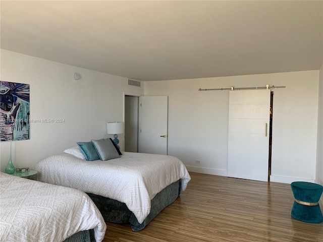 bedroom featuring a barn door and hardwood / wood-style flooring