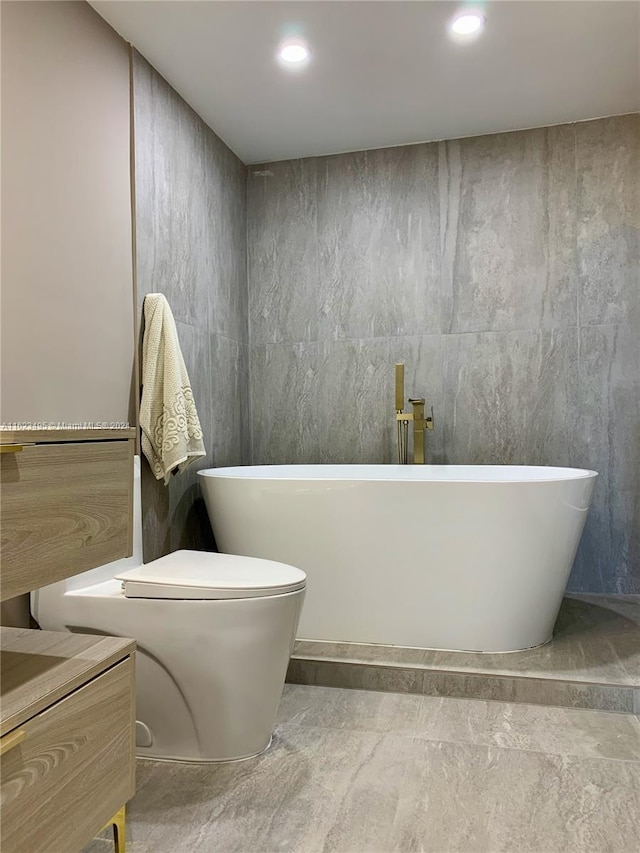 bathroom with tile walls, vanity, toilet, and a washtub