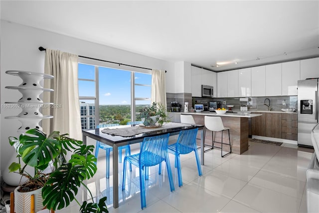 kitchen featuring stainless steel appliances, a kitchen island, white cabinetry, light countertops, and modern cabinets