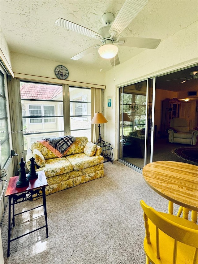 carpeted living room featuring ceiling fan and a textured ceiling